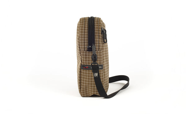 A side view of the Everyday Cubelet in Coyote Halcyon (brown with a white grid) showing the o-ring attachment point and included 5/8" strap.